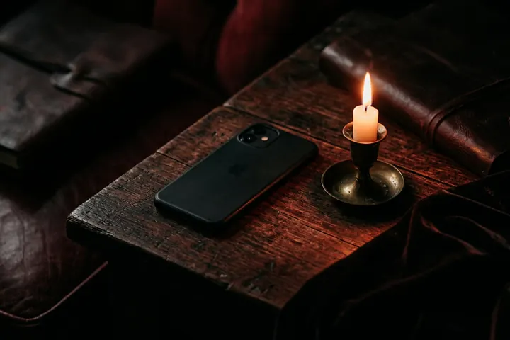 Téléphone posé face contre table à côté d'une bougie allumée, ambiance feutrée